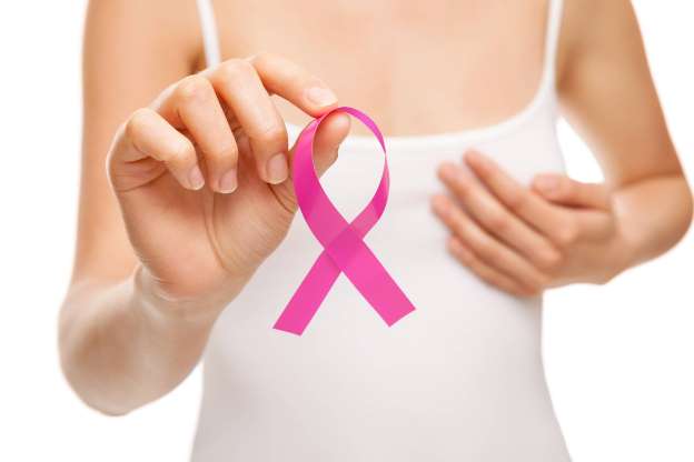 Mulher segurando laço cor-de-rosa da campanha Outubro Rosa de prevenção ao câncer de mama