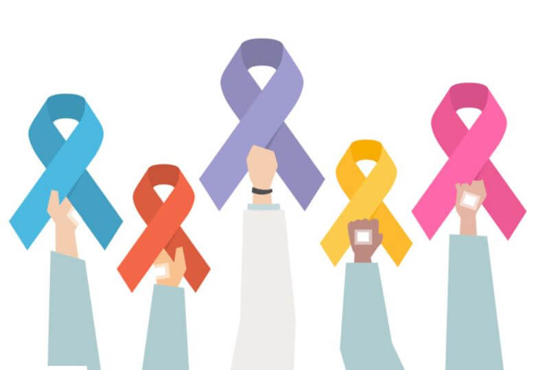 Mãos segurando lacinhos coloridos da campanha de prevenção contra o câncer